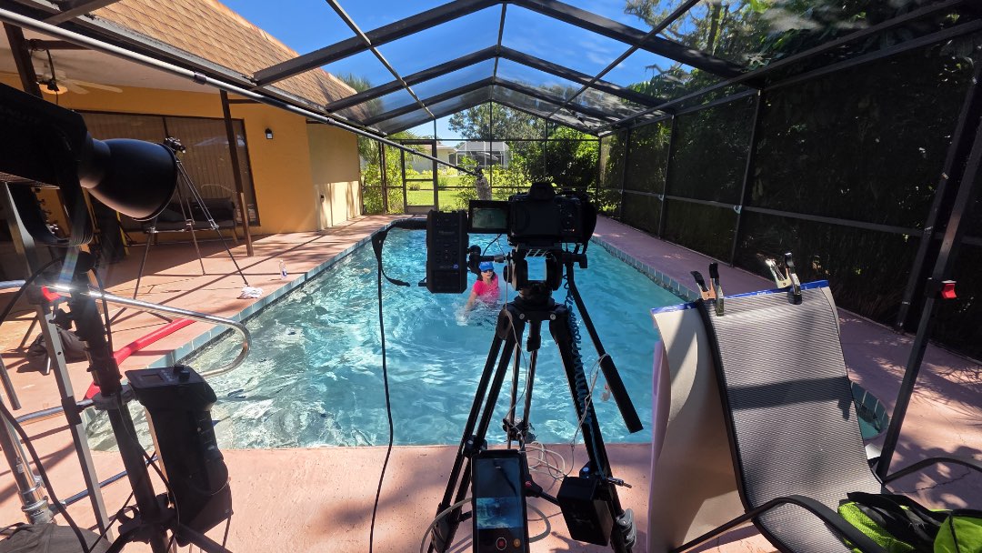 Filming a Fitmotivation aquatic fitness instructor video that showcases the use of a towel as equipment.